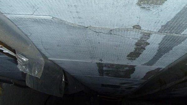 Bildet viser noen delvis forvitrede takplater i en mørk krypkjeller. Platene har synlige skader og sprekker.