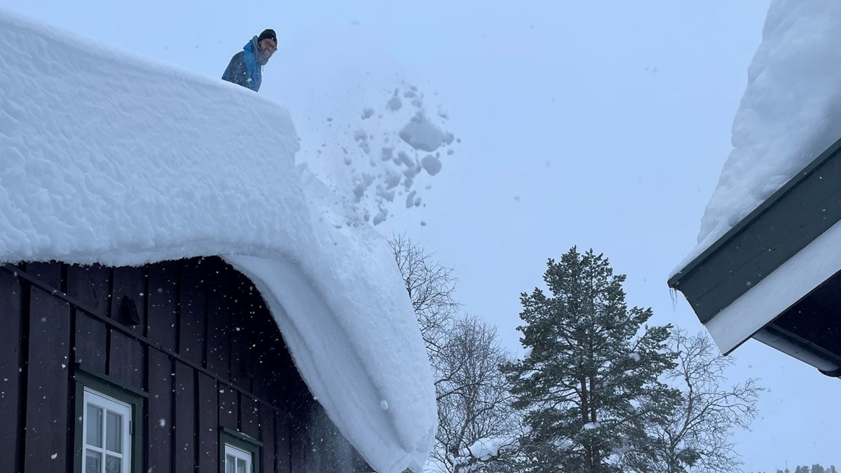 Mann måker snø av tak.