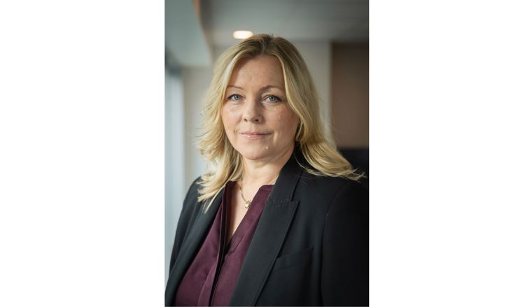Kvinne med lyst, skulderlangt hår ser inn i kamera.