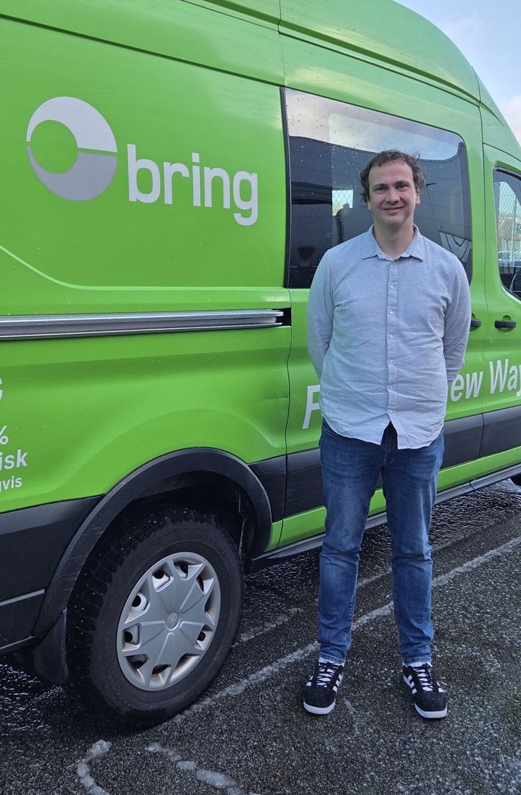 Bildet viser Bjørn Slettebø, sjef for kvalitet og utvikling i Posten Bring Varebil AS, som står foran en grønn varebil. 