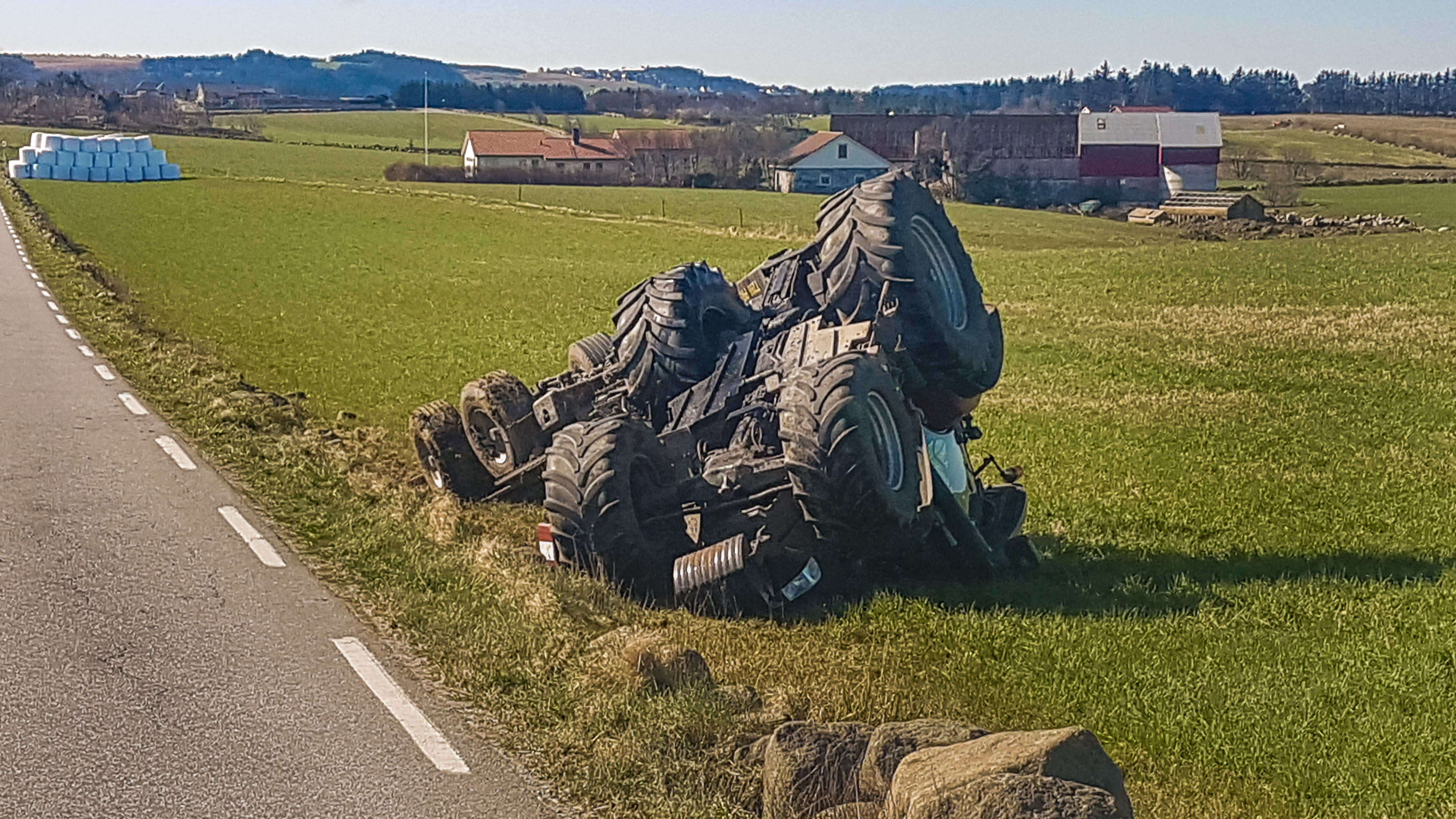 Veltet traktor som ligger ved siden av en veg. Foto.