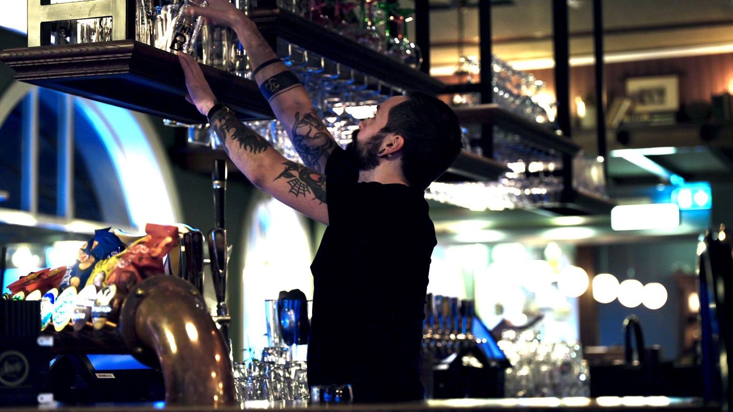 En mannlig bartender er på jobb bak baren. 