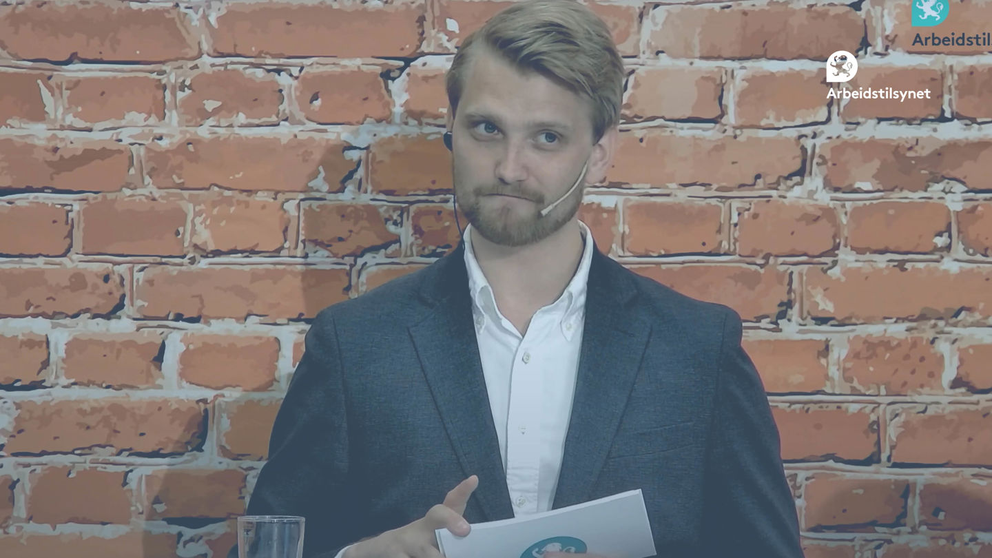 Bilde fra webinaret av programlederen. Han sitter foran en murvegg og har talekort i hendene.