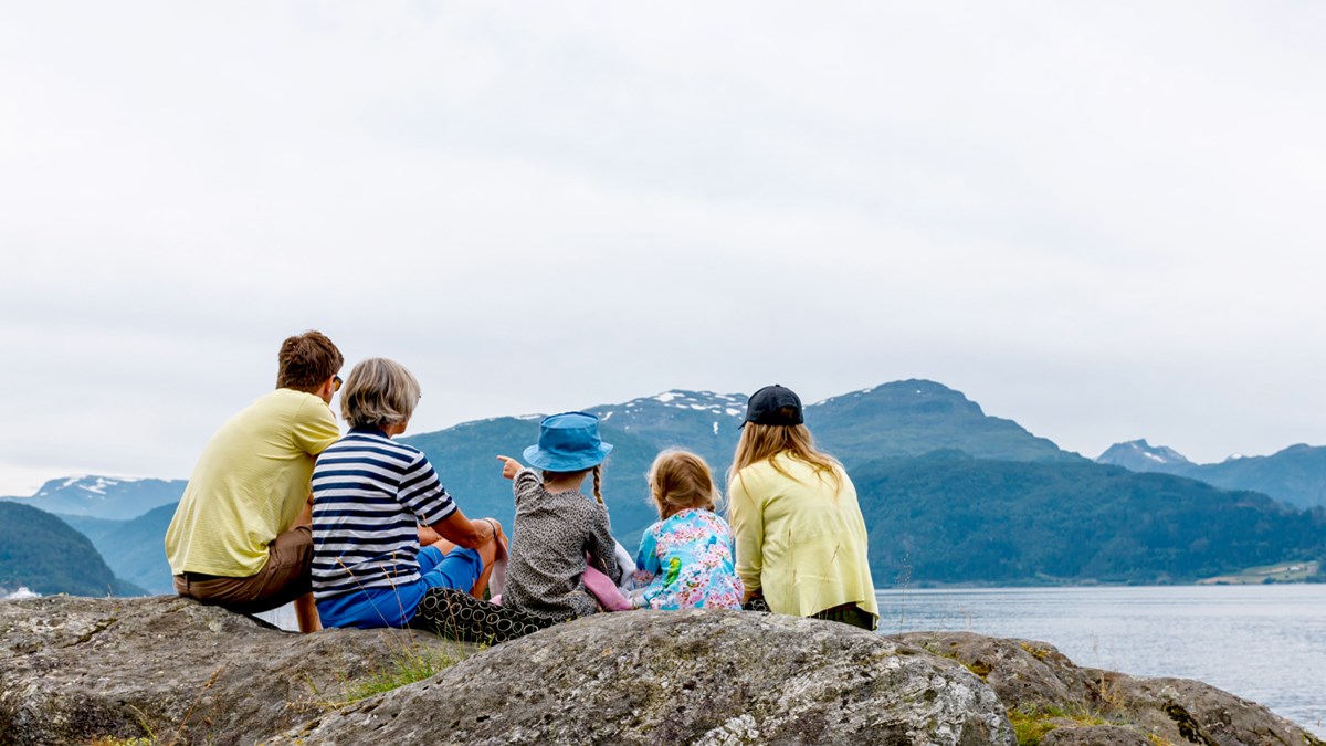Bildet viser en familie på en fjellknaus med utsikt over havet