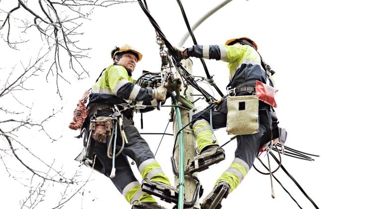 To arbeidere som jobber i en høyspentmast