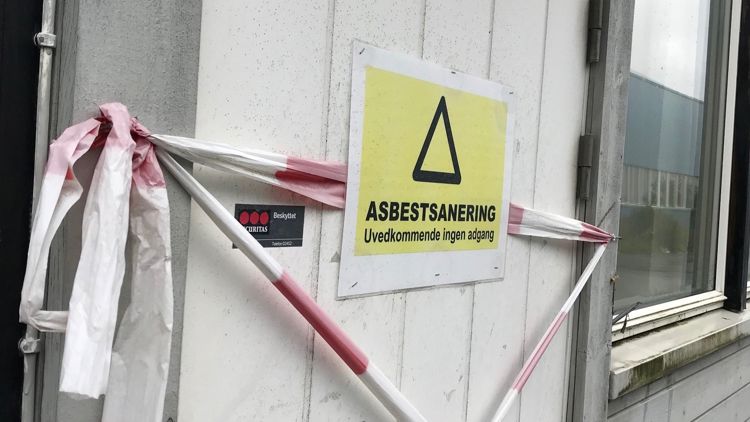 Bilde av sperrebånd på en vegg der det foregår arbeid, og en plakat som sier at det foregår asbestsanering