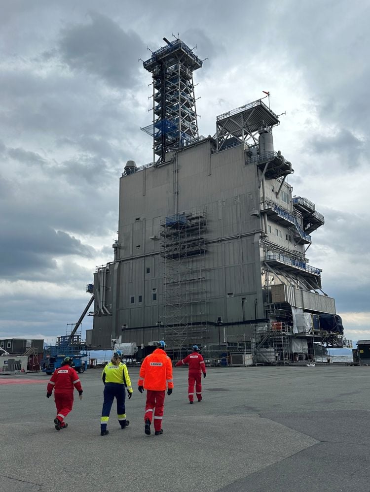 Flere arbeidere går mot en nybygd del av en nybygd del av en oljeplattform som ligger på land 