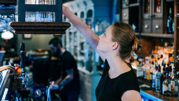 Bildet viser en kvinnelig servitør i en bar.