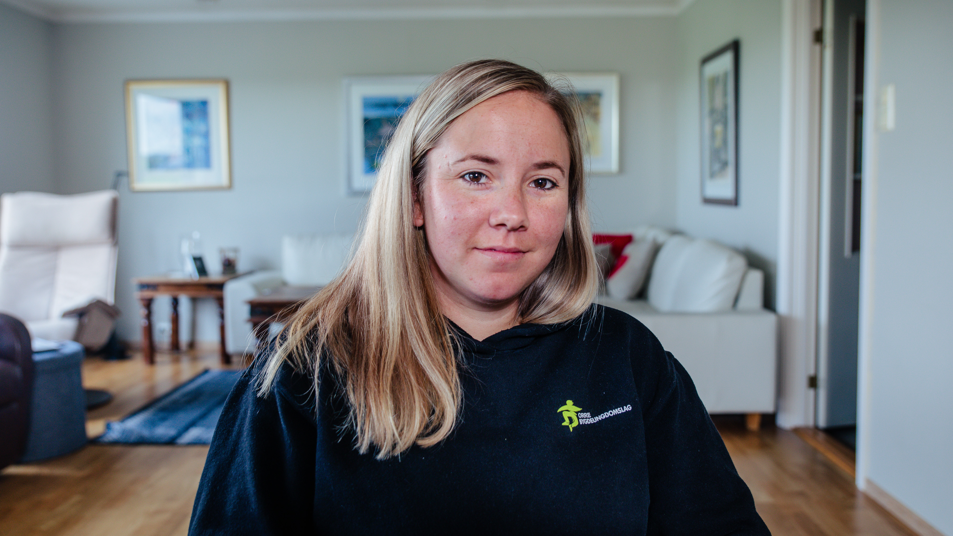 Ailin Skårland sitter i stua si. Foto.